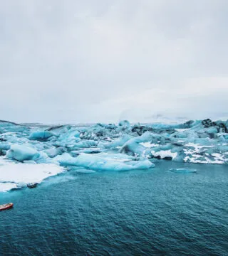 Man paddle boarding near iceberg - Cadillac Travel