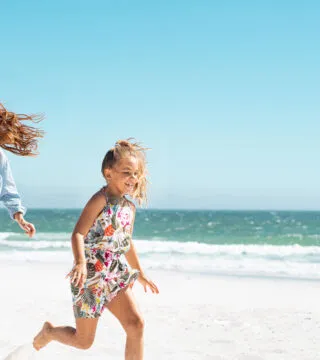 Family running on a beach - Cadillac Travel