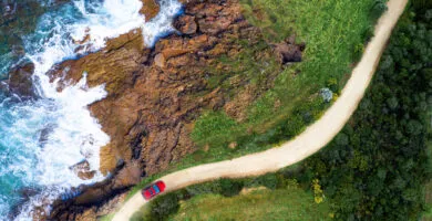 Red car driving along dirt road - Cadillac Travel