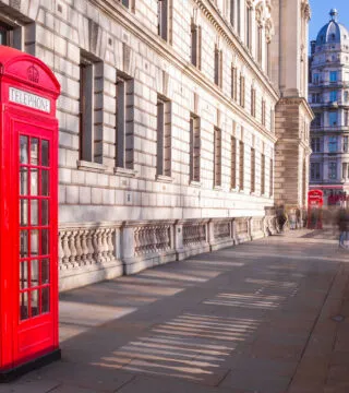 Red phone box in London with Big Ben in the background - Cadillac Travel