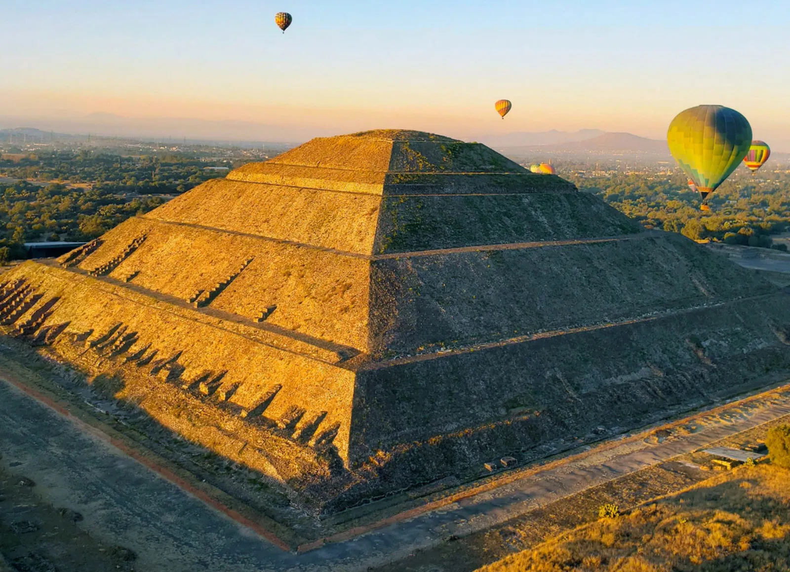 mexican temple during sunset with hot air balloons in the background - Cadillac Travel