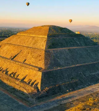 mexican temple during sunset with hot air balloons in the background - Cadillac Travel