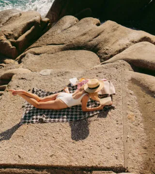 Woman relaxing and reading on the rocks - Cadillac Travel