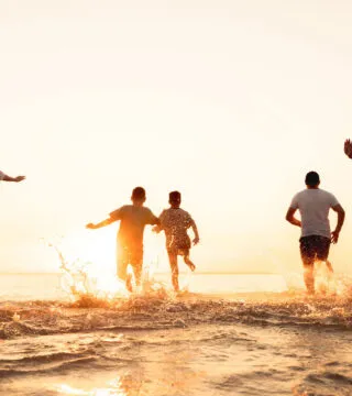 group of travellers running into the sea - Cadillac Travel