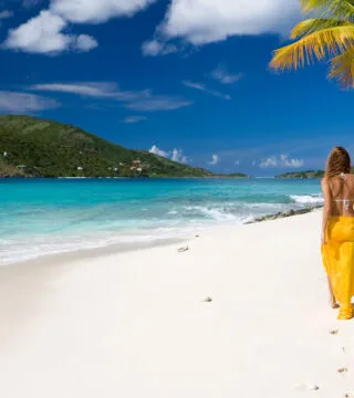 Woman walking on a tropical beach - Cadillac Travel