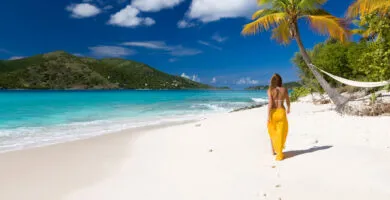 Woman walking on a tropical beach - Cadillac Travel