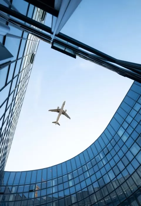 Modern building glass facade with airplane in clear sky - Cadillac Travel